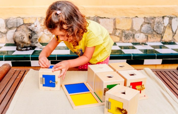 niña jugando con una caja de permanencia Montessori más compleja Caja de permanencia Montessori