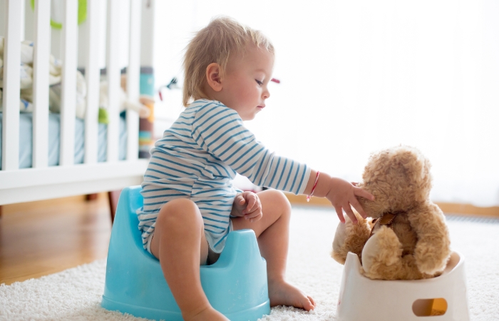 El peluche, también en un orinal, al lado del orinal del bebé Ayúdate de muñecos con orinal