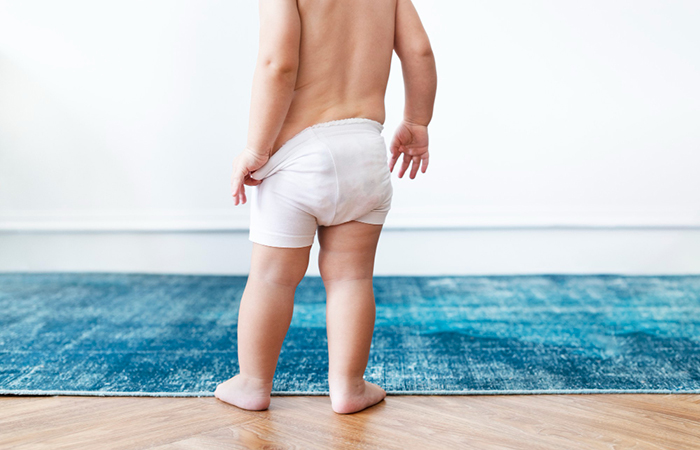 niño que se quita la ropa para ir al baño niño camino del baño