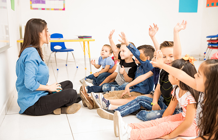 Niños en el aula piden la palabra levantando el brazo Valores de la Navidad: respeto