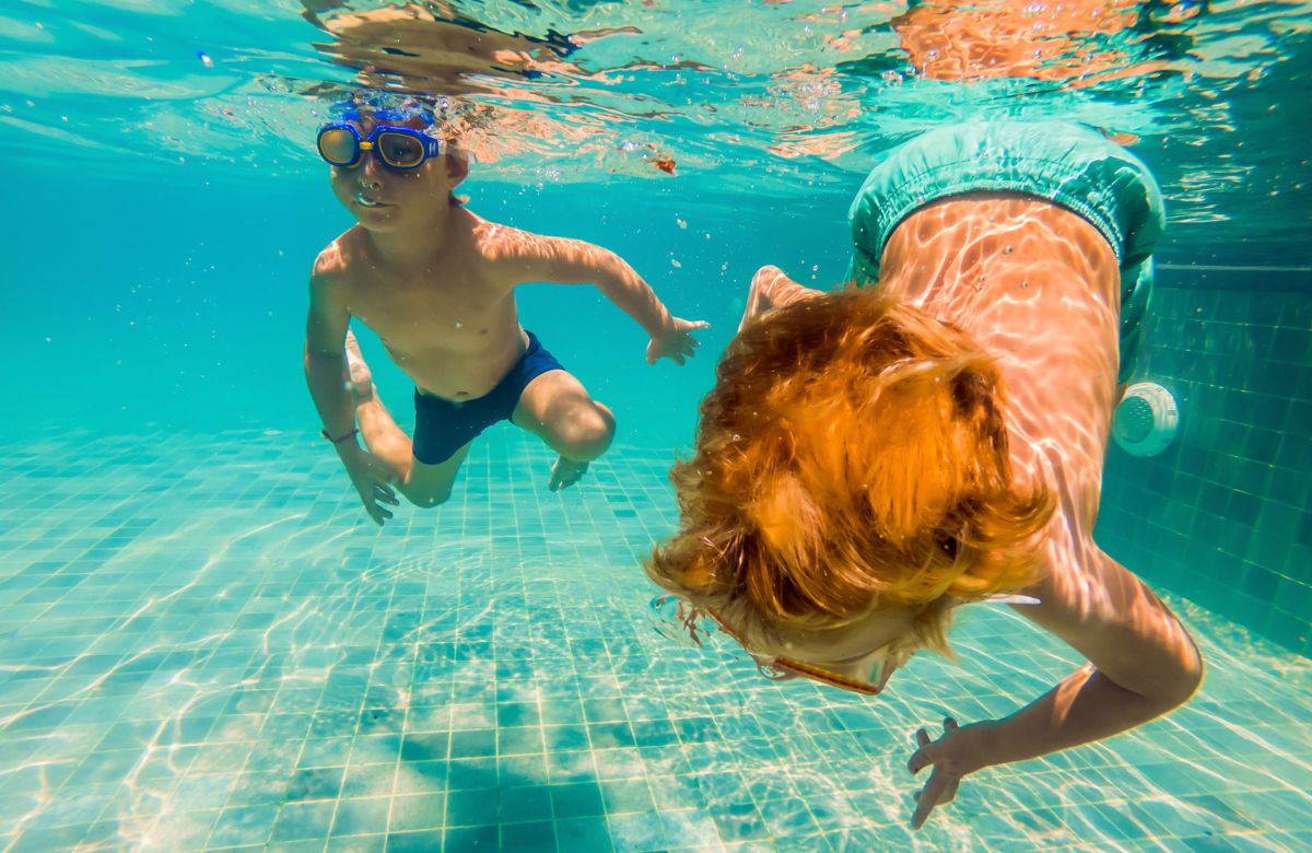 dos niños buceando con gafas de bucear y buscando objetos en el fondo Buceando y buscando objetos en el agua