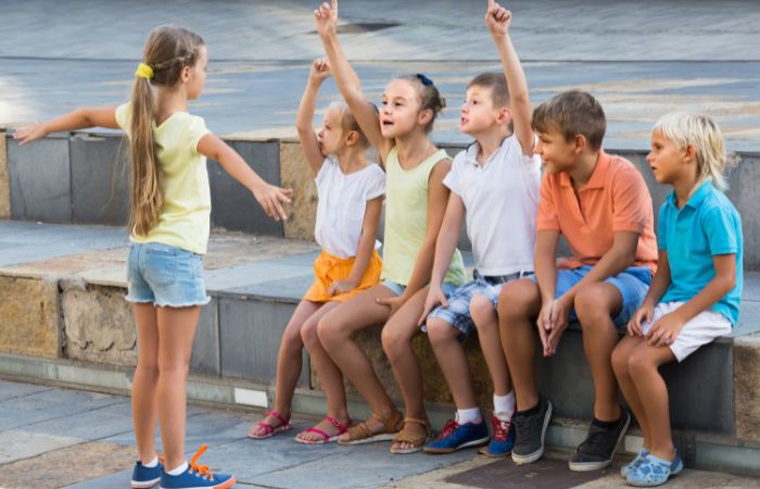 Niña haciendo gestos ante un grupo de amigos que juegan con ella juegos de m´´imica
