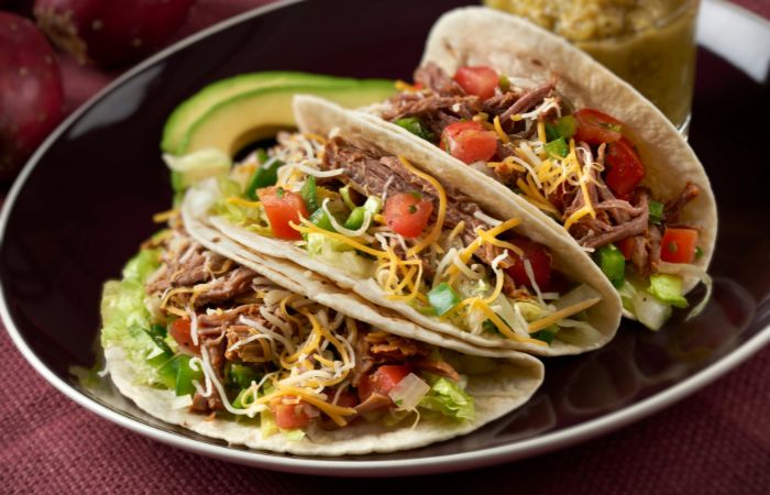 Tacos con lechuga, pimiento, tomate y queso rallado Tacos